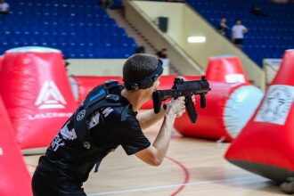 Игрок LASERWAR занимает позицию у красного надувного укрытия.